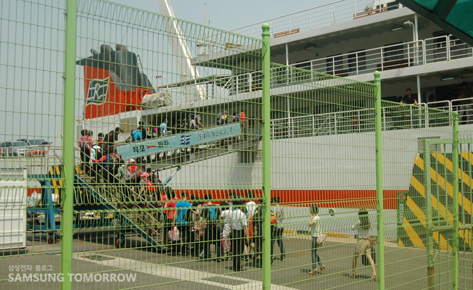 펜스 뒤로 보이는 승선하는 사람들