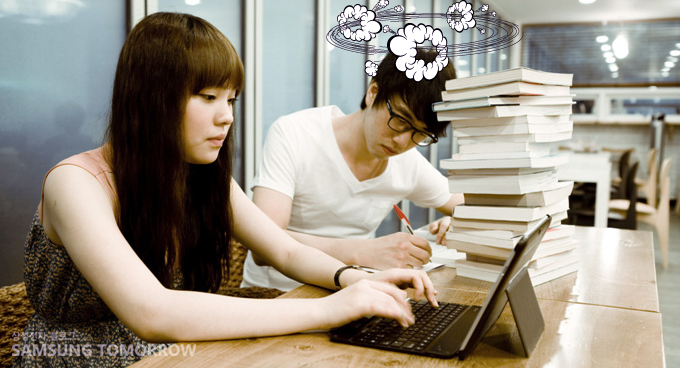 갤럭시 탭을 가진 여자와 책을 쌓아논 남자