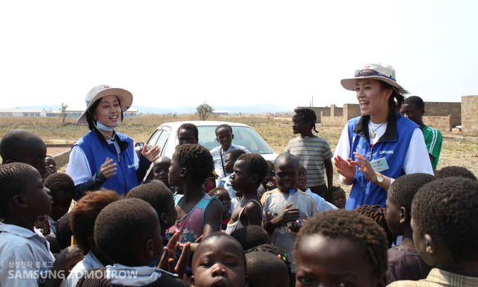 잠비아 아이들과 노래를 부르는 자원봉사자들