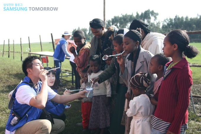 비누방울을 불고 있는 에티오피아 사람들과 자원봉사자