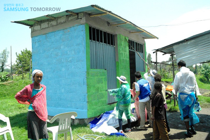 벽에 페인트를 친하는 자원봉사자