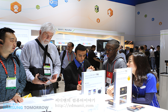 많은 분들이 갤럭시탭 7.7 테이블 앞에서 이야기를 나누는 모습