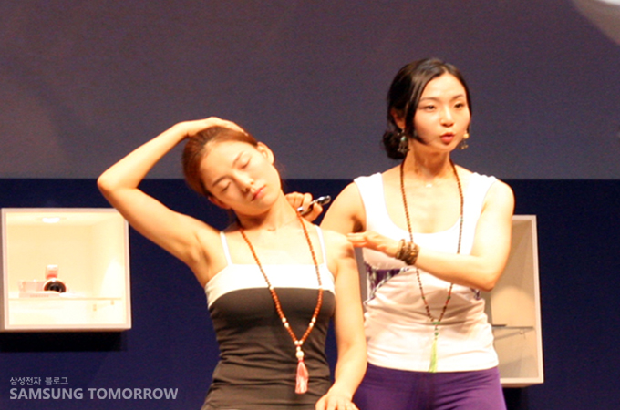 요가강연하는 에리카와 자세를 보여주는 여성