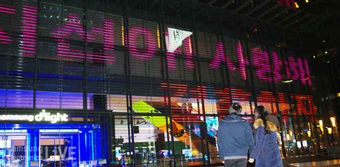 딜라이트 옥외광장 미디어 파사드에 커다란 문구를 보는 커플