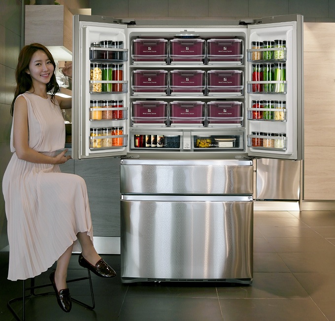 열려있는 냉장고 옆에 앉은 모델