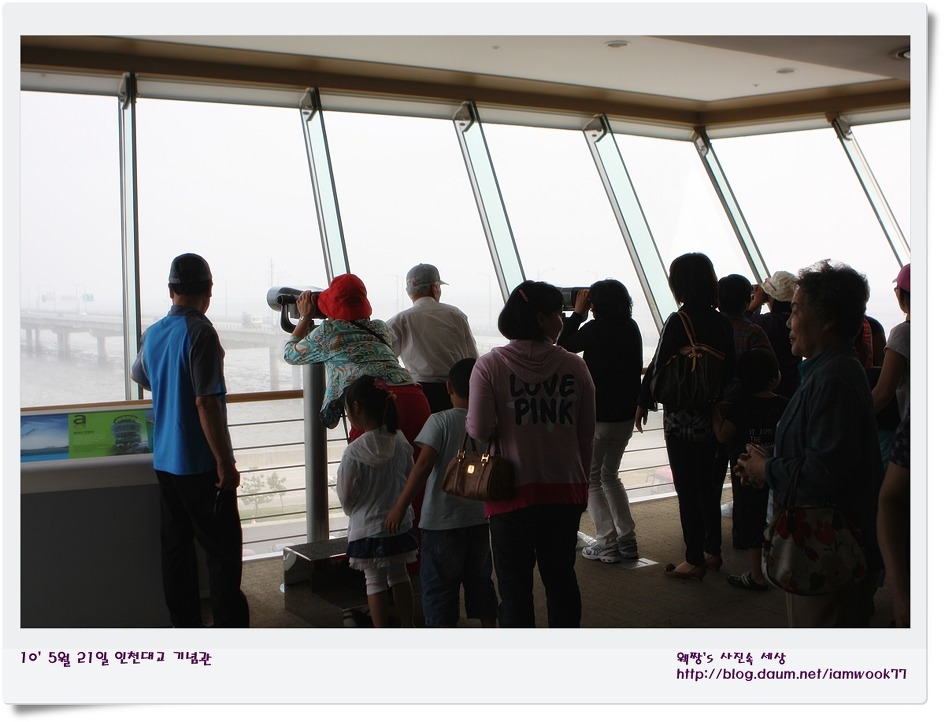 전망대에서 망원경으로 다리를 보는 관람객들