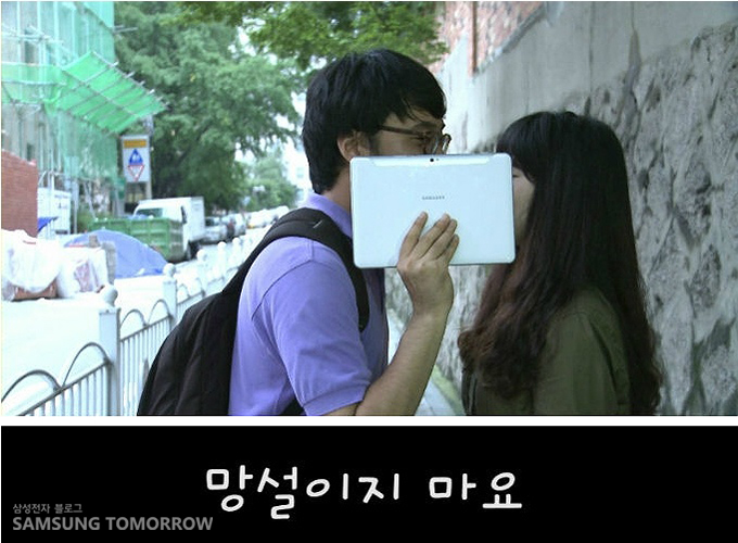 갤럭시탭으로 가리고 뽀뽀하려는 남성과 여성