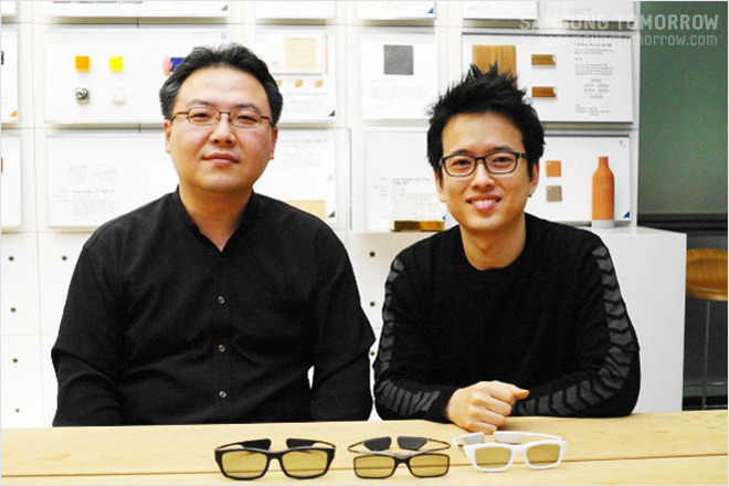 안경을 앞에두고 함께 사진 찍는 디자이너와 선임