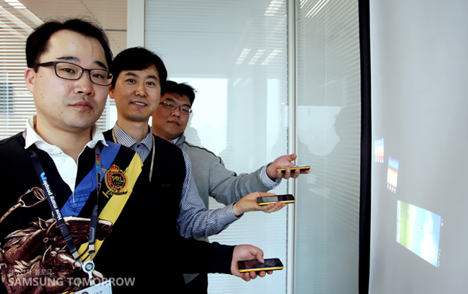 스크린에 갤럭시빔을 쏘고 있는 개발자들