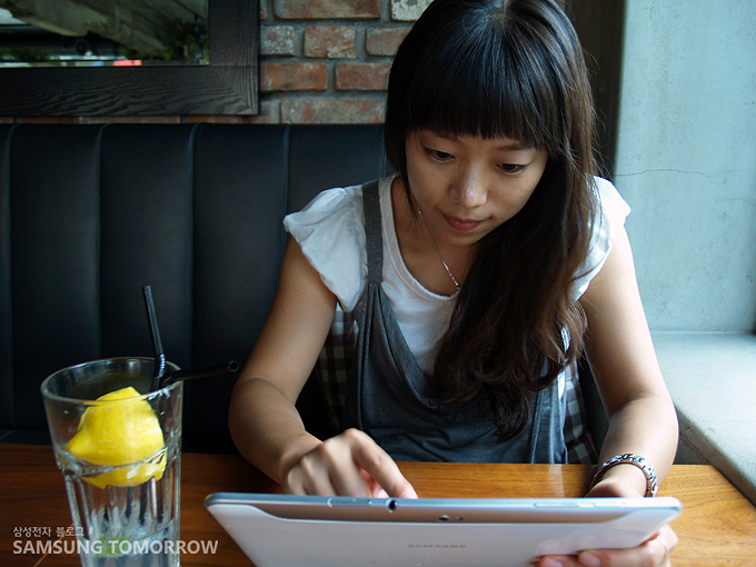 레모네이드와 함께 갤럭시탭을 만지는 여성