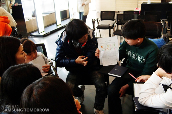 상상속의 휴대폰의 모습을 말하고 있는 초등학생의 모습