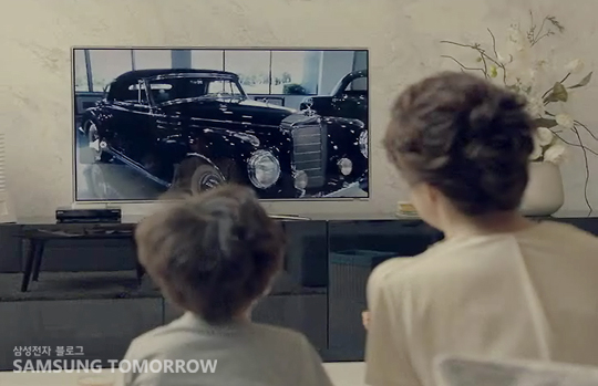 티비에 나오는 자동차를 유심히 보는 아이와 엄마