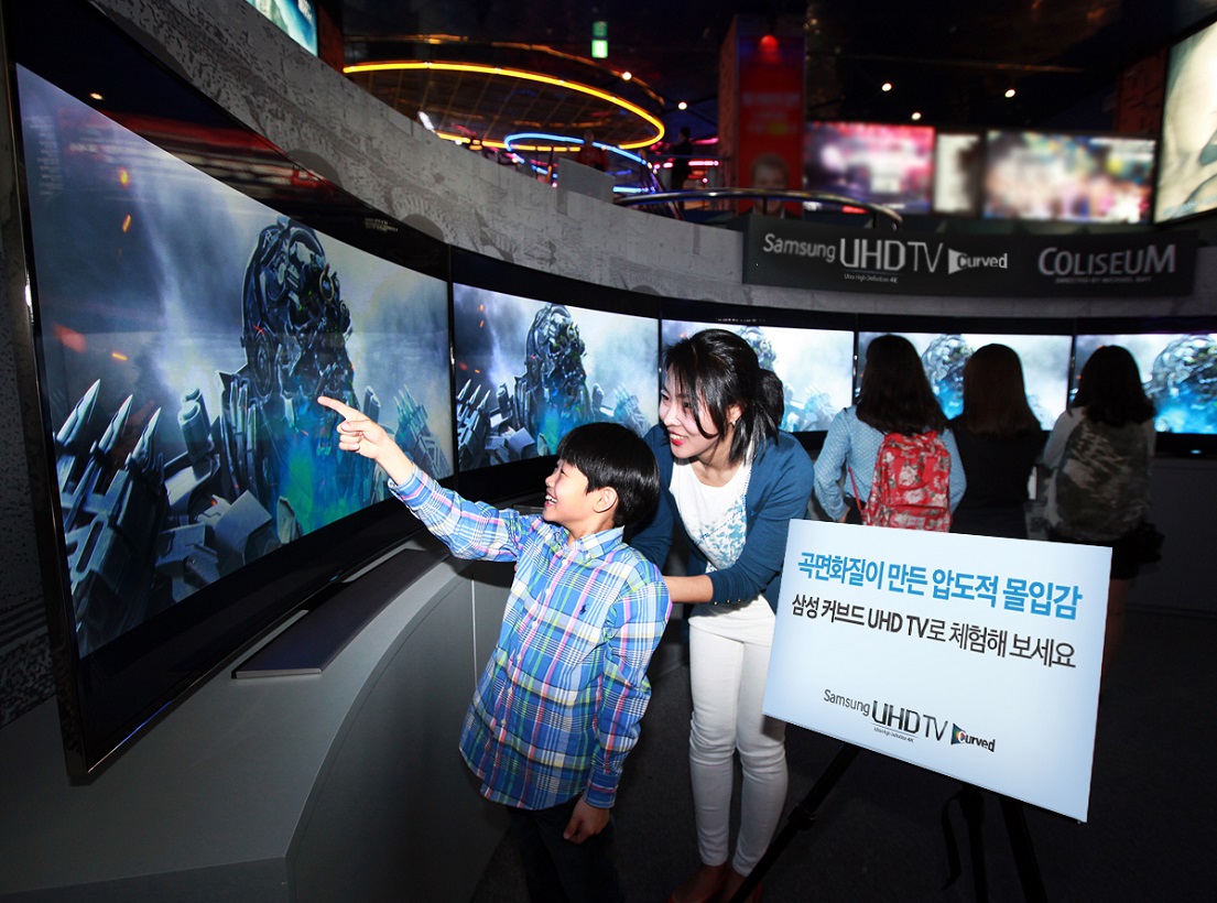 65형 삼성 커브드 UHD TV 7대를 곡면 형태로 연결한 '커브드 UHD 콜로세움 쇼케이스'를 관람객들이 살펴보고 있는 모습입니다.
