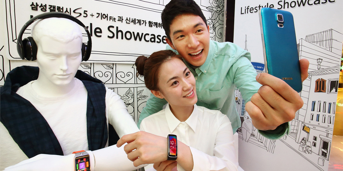 고객들이 생활 속 갤럭시 S5와 기어 핏의 사용성을 보여주는 마네킹 옆에서 같은 상황을 연출해보는 모습