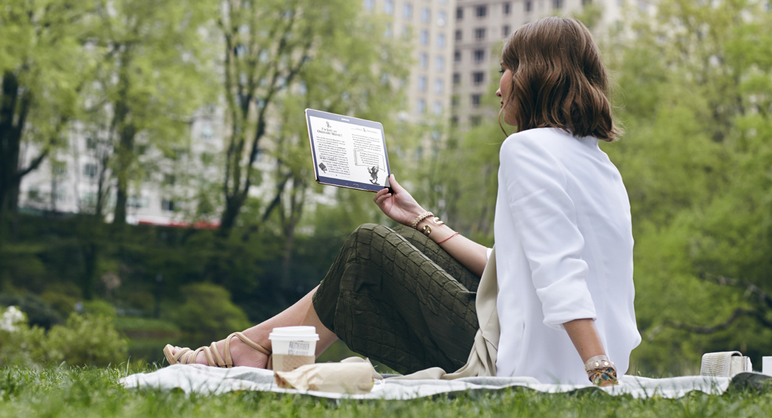 잔디밭에서 갤럭시 탭 s를 들고 있는 여성 이미지입니다.