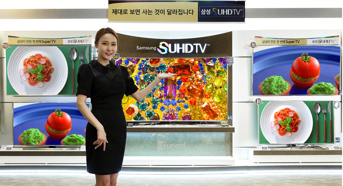 제대로 보면 사는 것이 달라집니다 삼성 SUHD TV란 판넬 아래 제품이 전시돼 있고 모델이 이를 가리키고 있습니다.