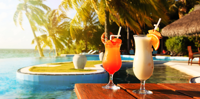 휴가지 전경과 함께 아름다운 색상의 칵테일 두 잔이 보입니다