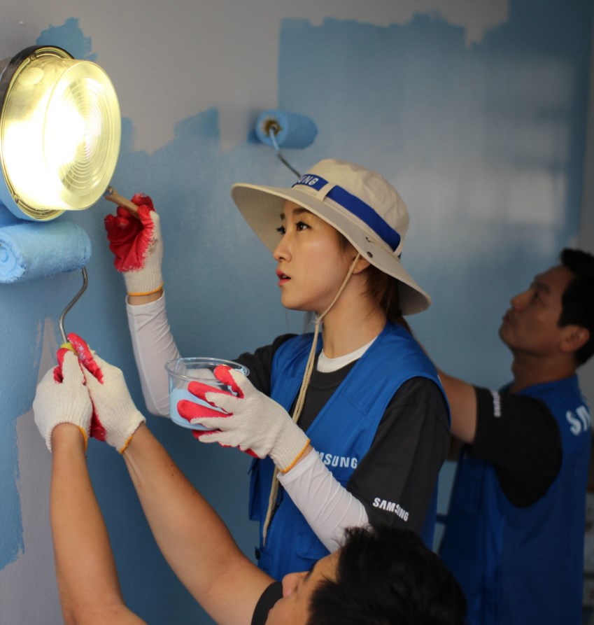 벽에 페인트를 칠하는 봉사단원들