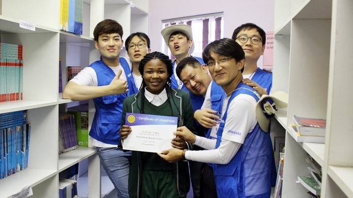 남아공 봉사단 스마트폰 수리 교육 팀은 모든 과정을 이수한 학생들에게 수료증을 발급했습니다. 사진은 수료증을 받아 든 채 활짝 웃고 있는 얀디스와(Yandiswa)양과 스마트폰 수리 교육 팀원들. (왼쪽부터 시계 방향으로)노주성 사원, 이병준 책임, 안치환 책임, 채종한 책임, 김인호 수석, 박찬호 선임