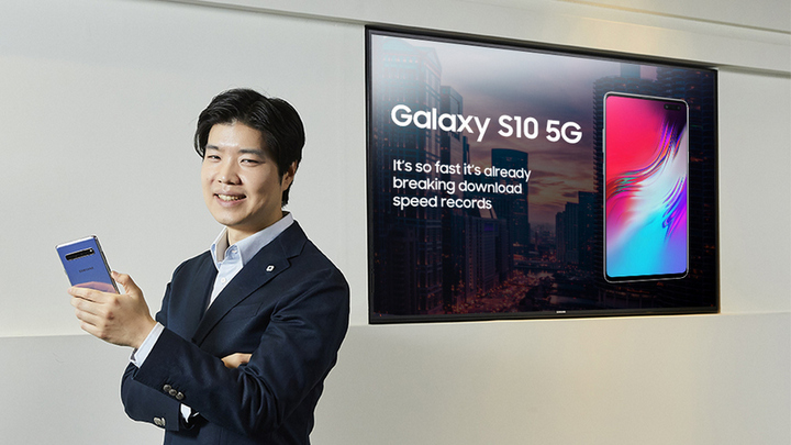 강호성 씨가 5G 디스플레이를 배경으로 갤럭시 S10 5G 를 들고 웃고 있는 모습