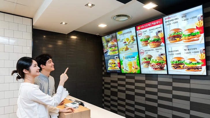 삼성전자 모델이 경기도 고양시에 위치한 맥도날드 고양삼송DT점에 설치된 삼성 스마트 사이니지를 소개하고 있다.