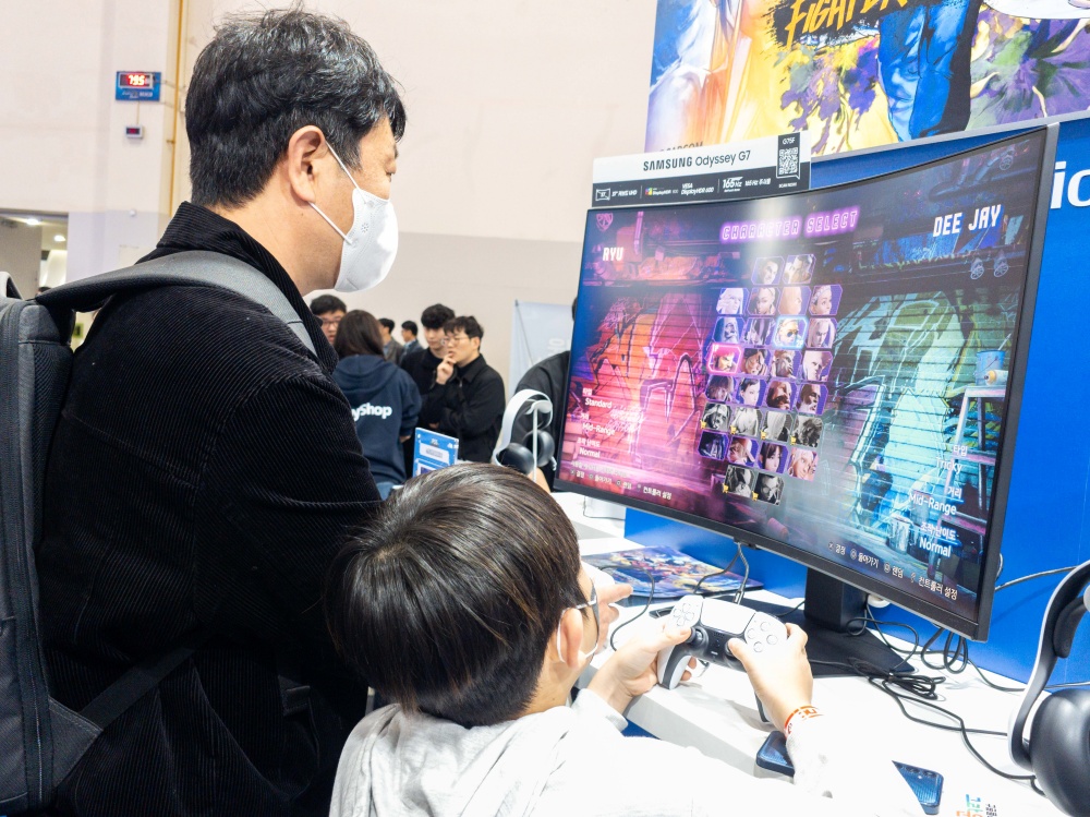 지스타 2025 PlayShop 부스에서 37형 대화면 오디세이 G7로 콘솔 게임을 즐기는 가족

