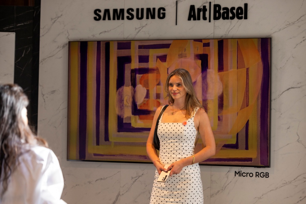 방문객이 삼성 마이크로 RGB 앞에서 포즈를 취하고 있다. 화면에는 'Art Basel in Basel 2026 컬렉션'에 수록된 아테네 갈리시아디스의 작품이 전시되어 있다.