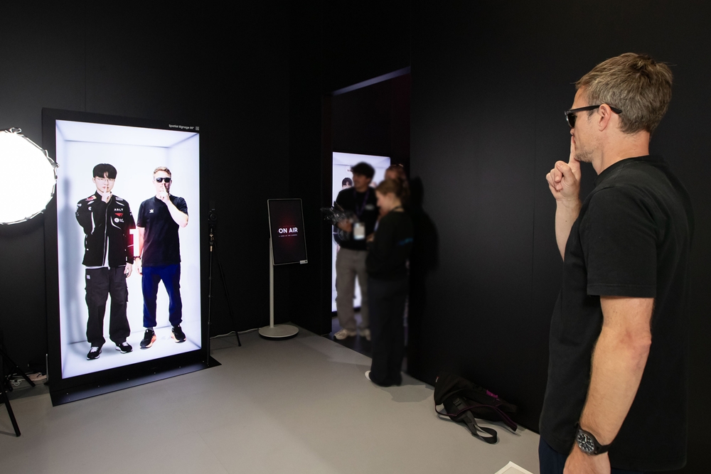 독일 쾰른에서 열린 '게임스컴(Gamescom) 2026' 삼성 부스 내 마련된 T1 포토존에서 한 관람객이 무안경 3D 디스플레이 '스페이셜 사이니지'를 통해 마치 T1 '페이커' 이상혁 선수와 함께 사진 찍는 듯한 체험을 하고 있다.